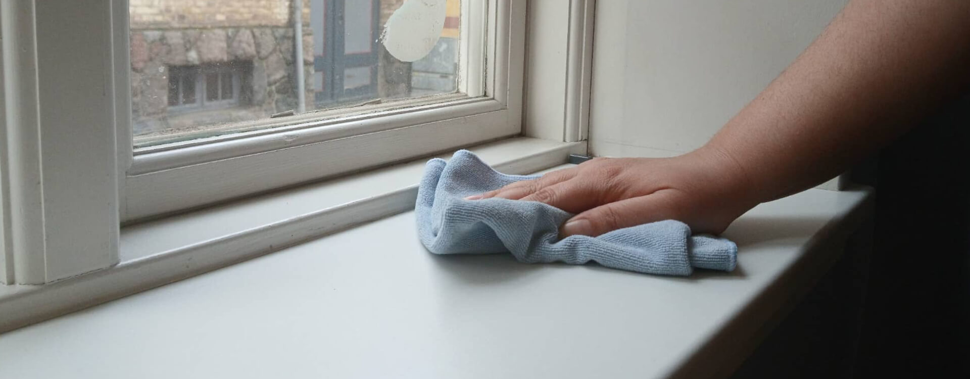 Hånd der aftørrer vindueskarm med mikrofiberklud – erhvervsrengøring i Odesne